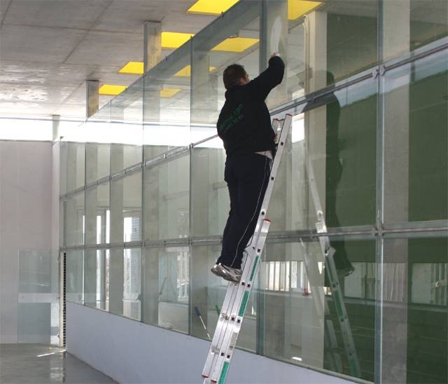 Trabajador sobre una escalera realizando la limpieza de cristales